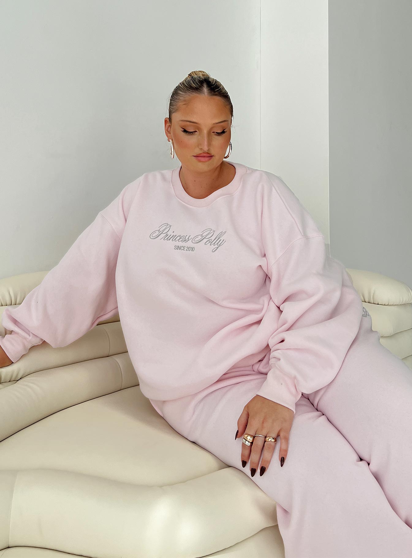 side view of model wearing Princess Polly Princess Polly Crew Neck Sweatshirt Script Baby Pink / Grey Curve 