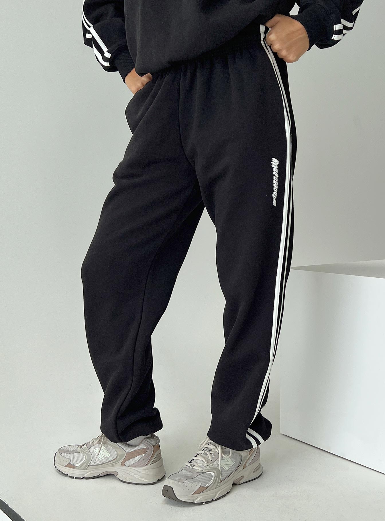 side view of model wearing Princess Polly Princess Polly Track Pants Stripe Black / White High Waisted Pants 