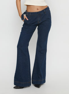 side view of model wearing Princess Polly Acapulco Low Rise Flare Jeans Dark Blue Wash Low Rise Jeans 