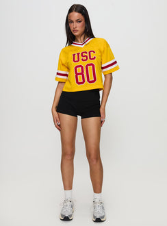side view of model wearing Princess Polly USC Football Jersey Gold Half Sleeves V-Neck 