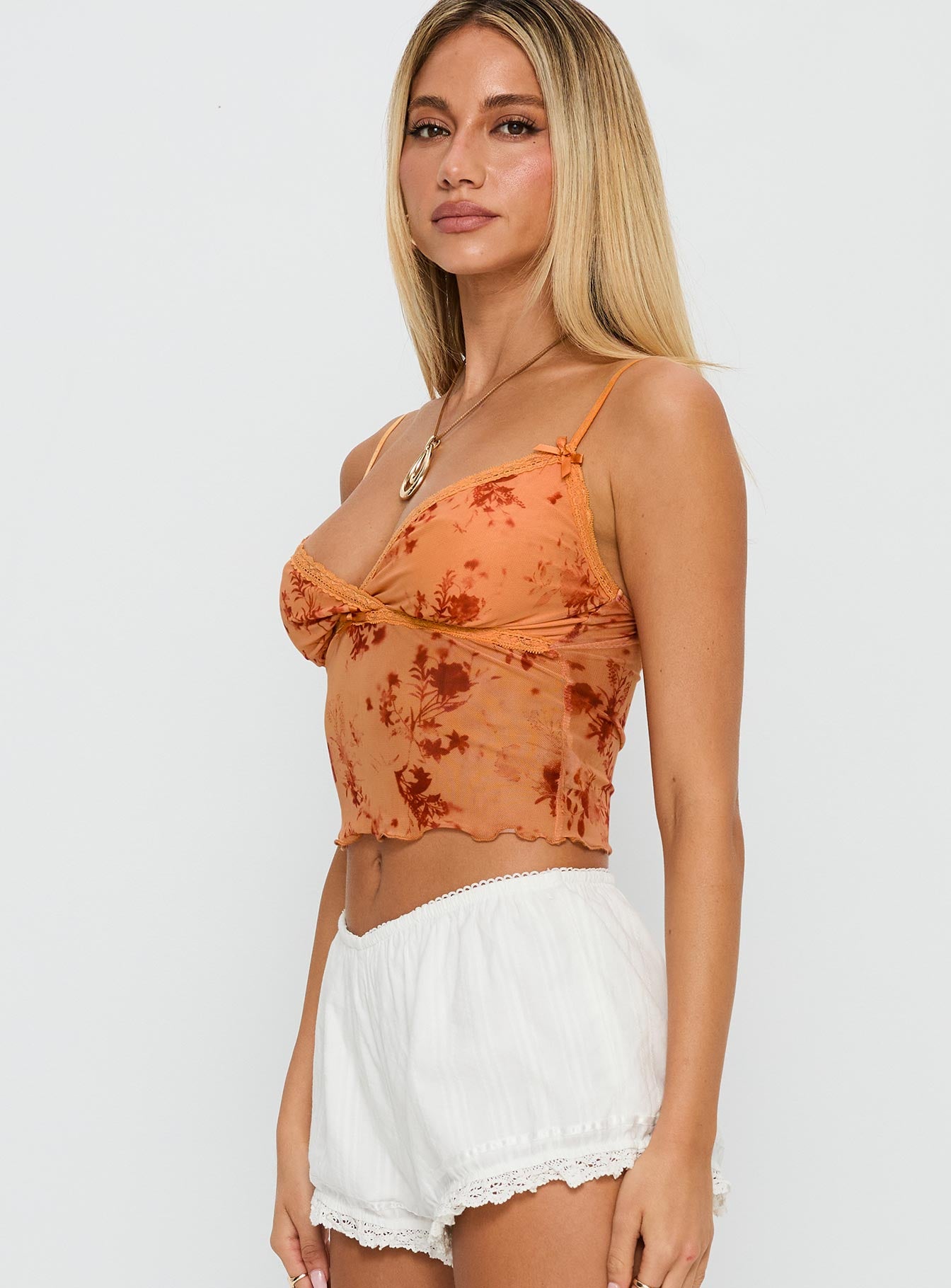side view of model wearing Princess Polly Shepherd Top Orange Floral Sleeveless V-Neck 