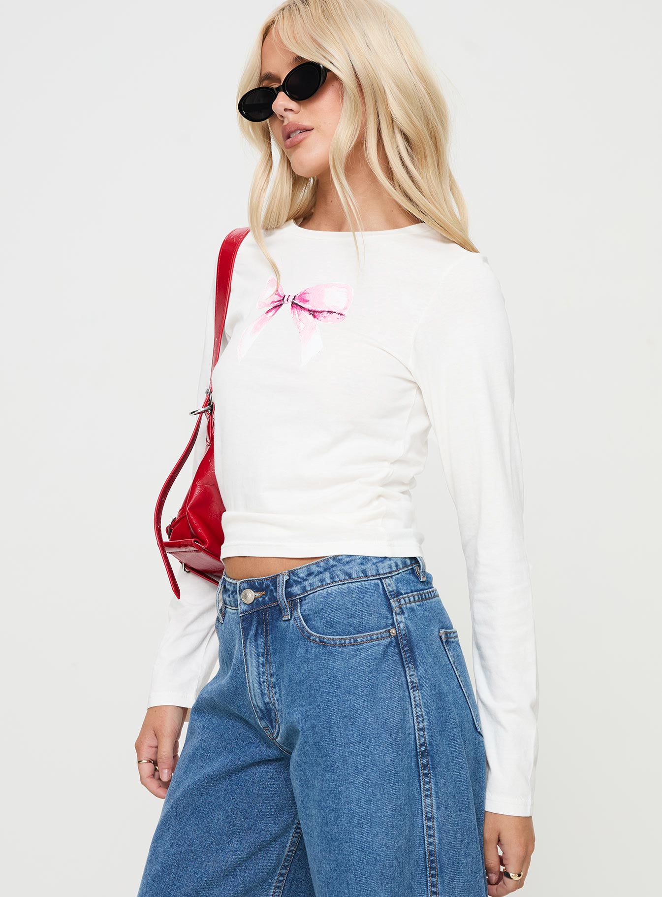 side view of model wearing Princess Polly Bow Baby Long Sleeve Top White Full Sleeves Full Sleeves Crew Neck Crew Neck 