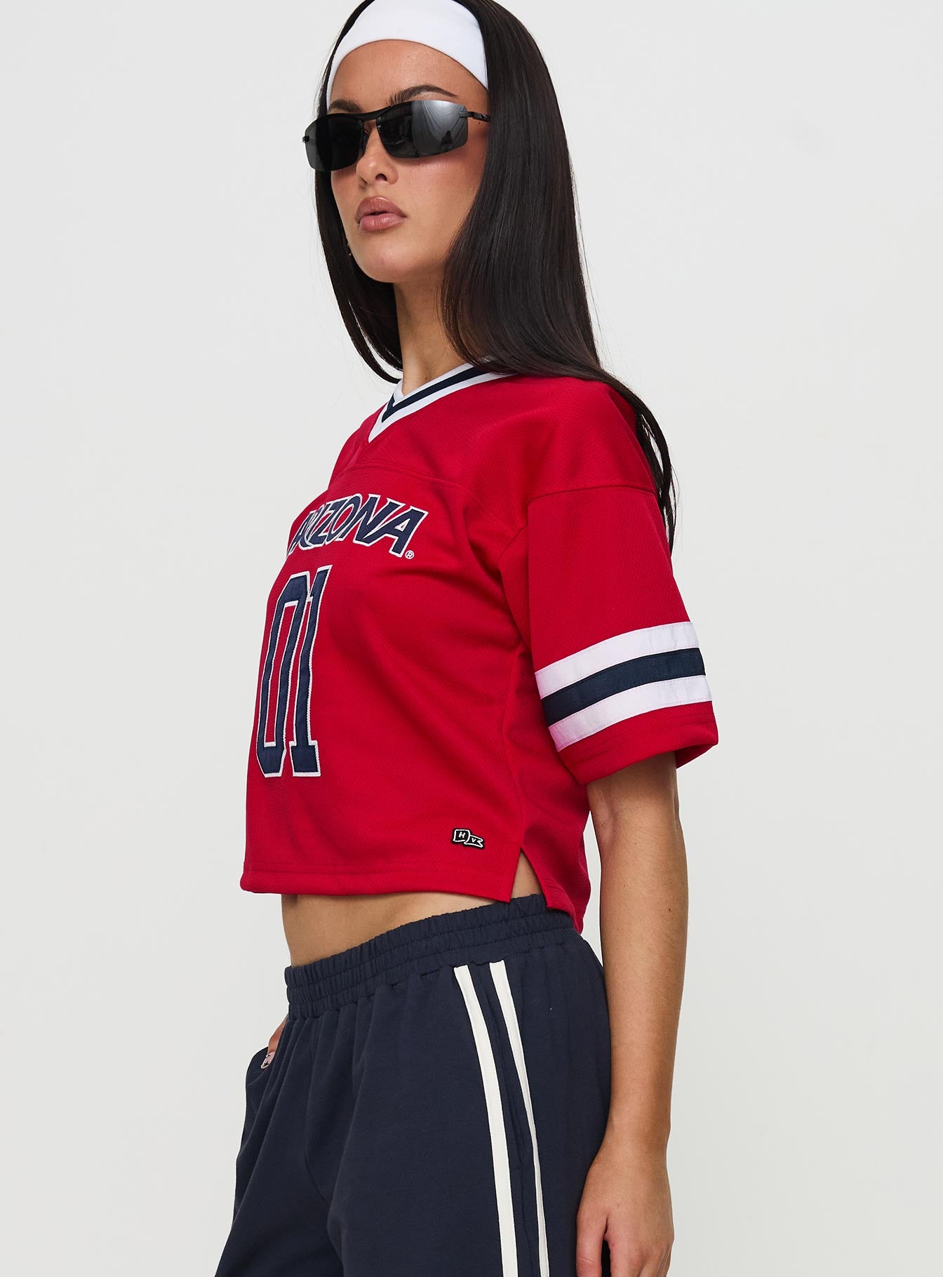 side view of model wearing Princess Polly U of A Football Jersey Red Half Sleeves V-Neck 