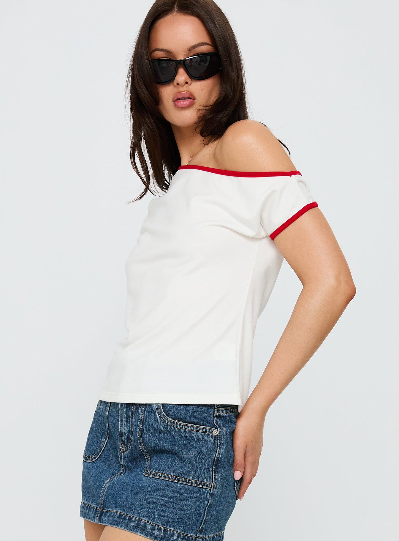 side view of model wearing Princess Polly Kelsa Off Shoulder Contrast Trim Top White / Red Short Sleeves Asymmetric Neckline 