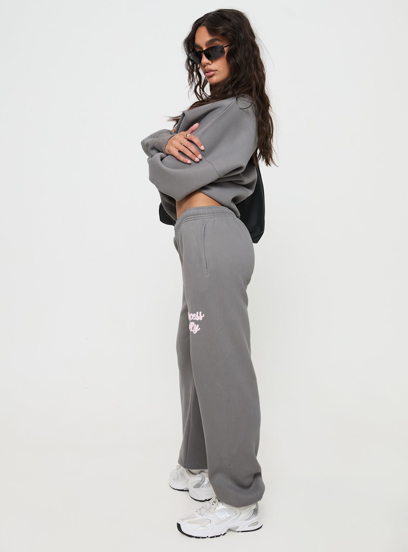 side view of model wearing Princess Polly Princess Polly Track Pants Puff Text Charcoal 