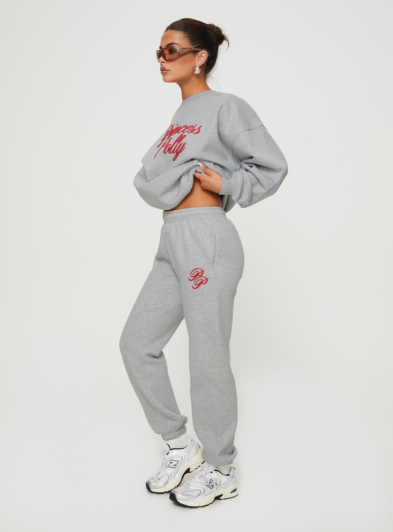side view of model wearing Princess Polly Princess Polly Track Pants Cursive Text Grey Marle/ Red High Waisted Pants 