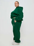 side view of model wearing Princess Polly Princess Polly Track Pants Script Green / Ivory Curve High Waisted Pants 