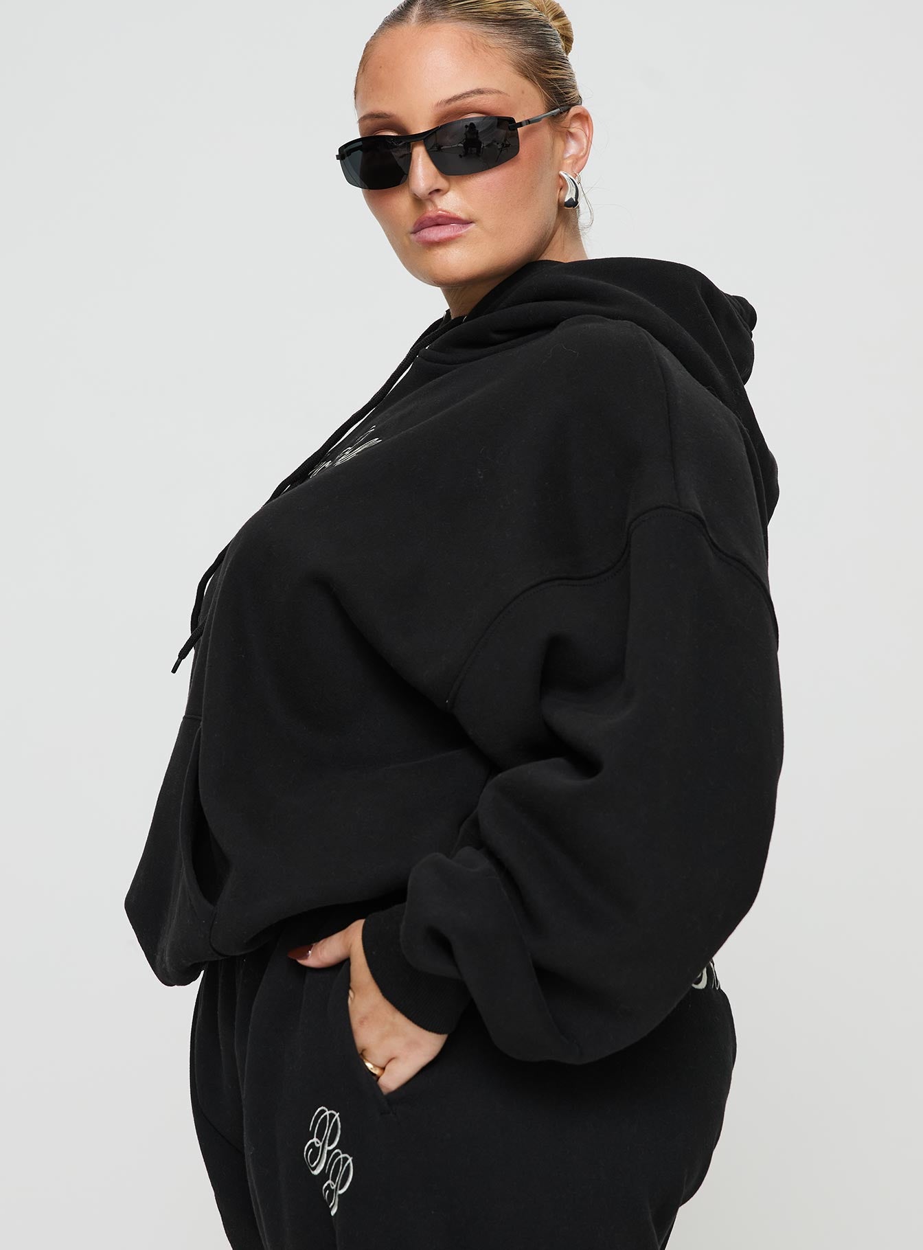 side view of model wearing Princess Polly Princess Polly Hooded Sweatshirt Script Black / Ivory Curve 