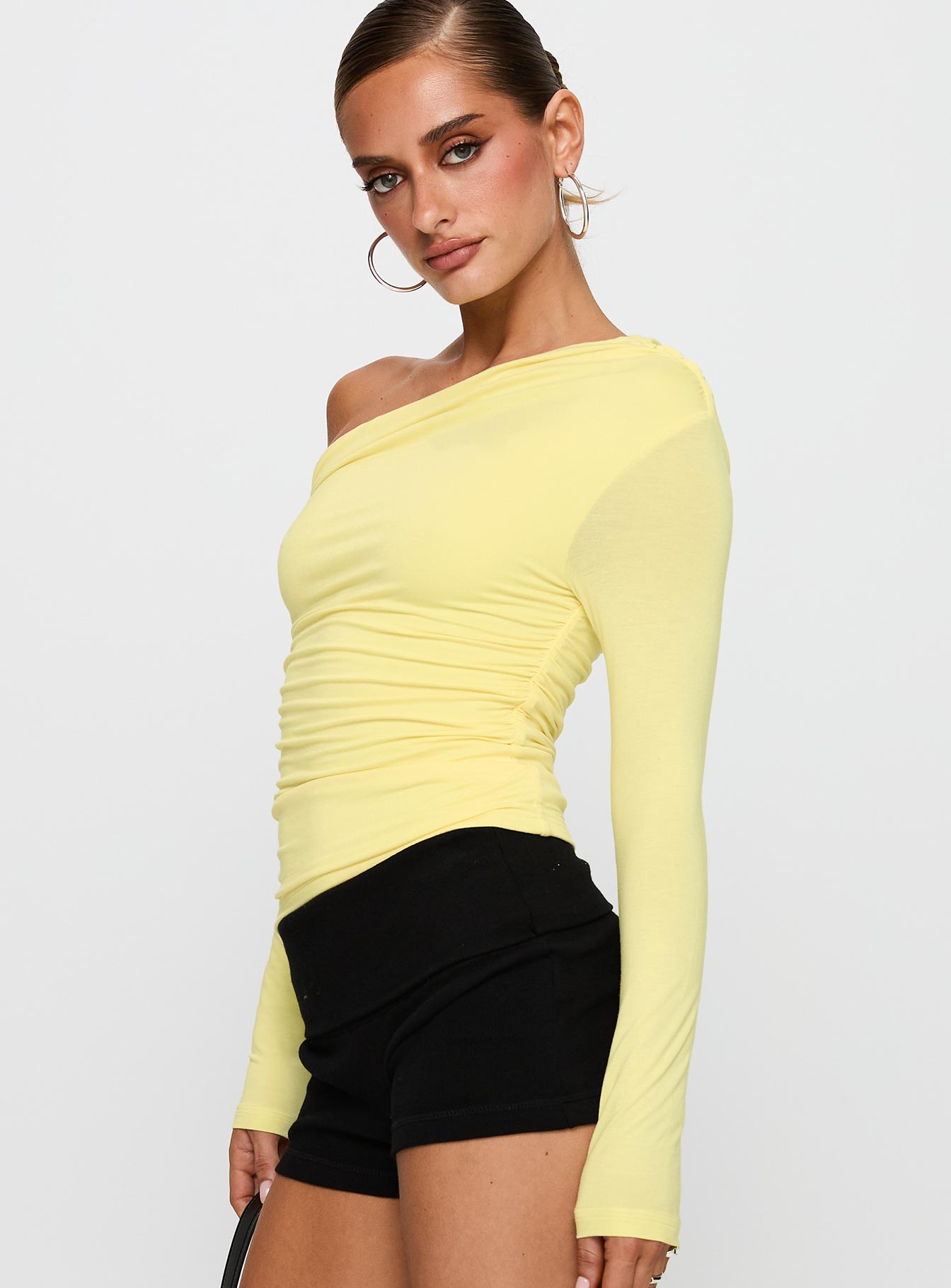 side view of model wearing Princess Polly Beller Long Sleeve Top Lemon Full Sleeves Asymmetric Neckline 