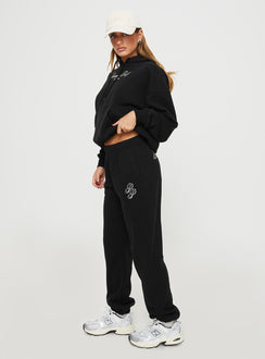 side view of model wearing Princess Polly Princess Polly Track Pants Script Black / Ivory High Waisted Pants 