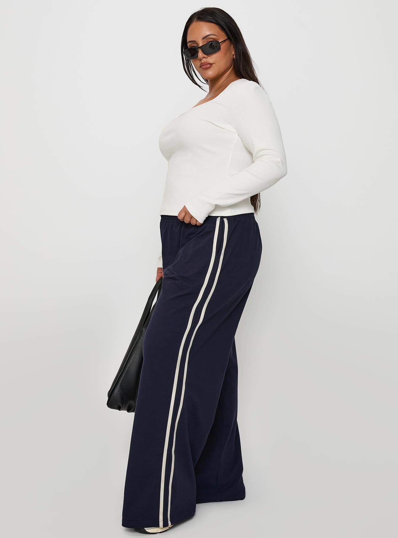 side view of model wearing Princess Polly Circuit Track Pants Navy Curve 