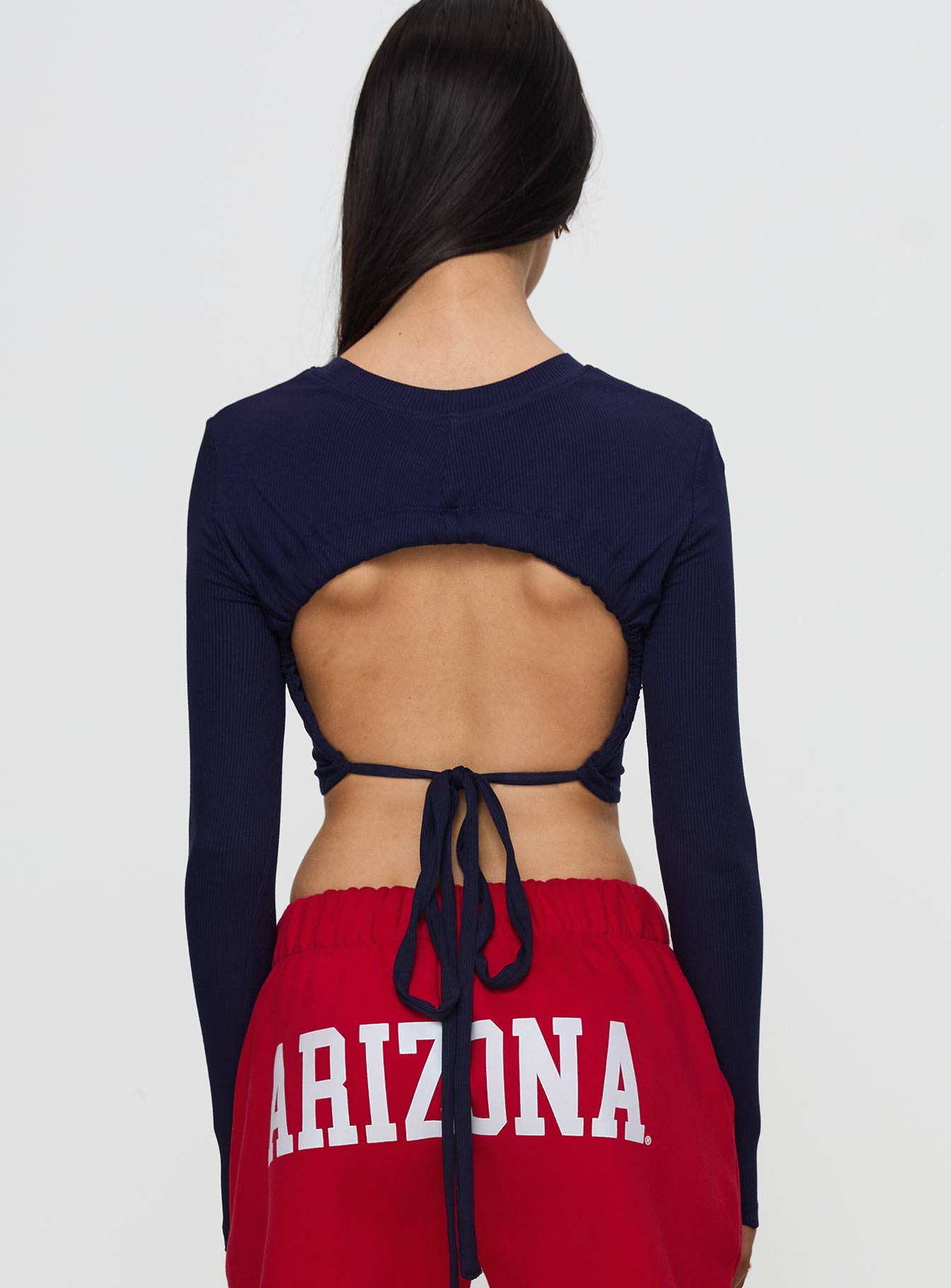 back view of model wearing Princess Polly U of A Bring It Back Long Sleeve Top Navy Full Sleeves Crew Neck 