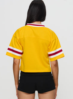 back view of model wearing Princess Polly USC Football Jersey Gold Half Sleeves V-Neck 