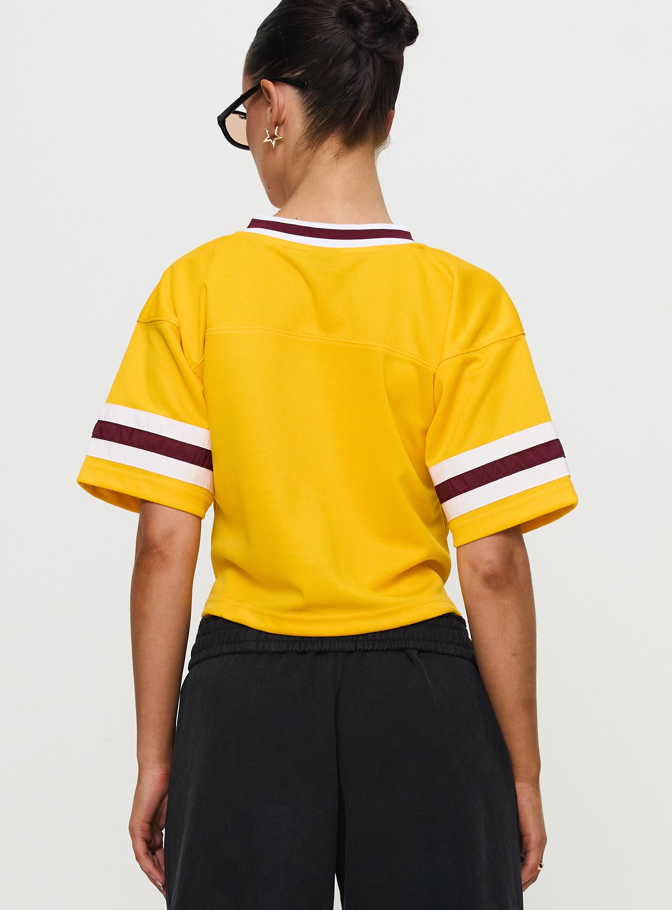 back view of model wearing Princess Polly ASU Football Jersey Gold Half Sleeves V-Neck 
