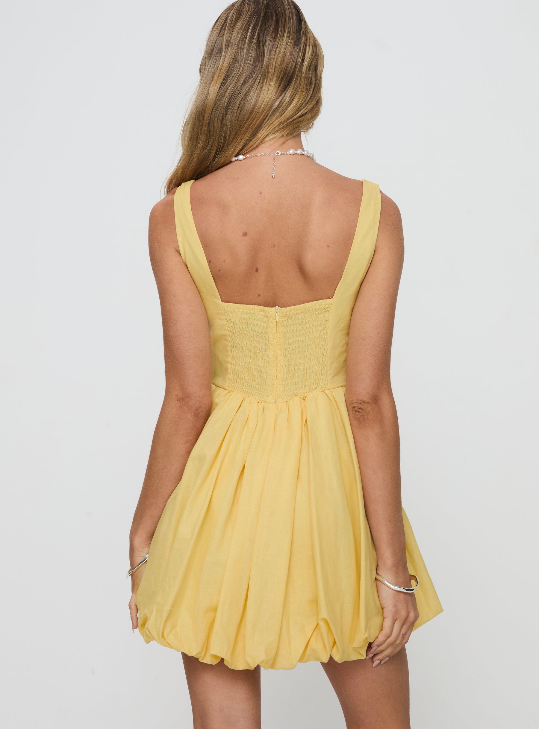 back view of model wearing Princess Polly Alcott Bubble Hem Mini Dress Lemon Square Neck 