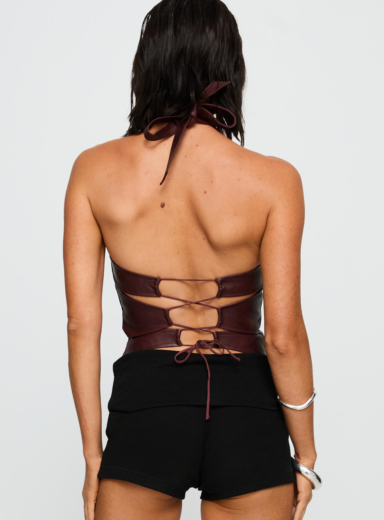 back view of model wearing Princess Polly Treat You Better Ring Detail Faux Leather Top Burgundy Sleeveless Asymmetric Neckline 