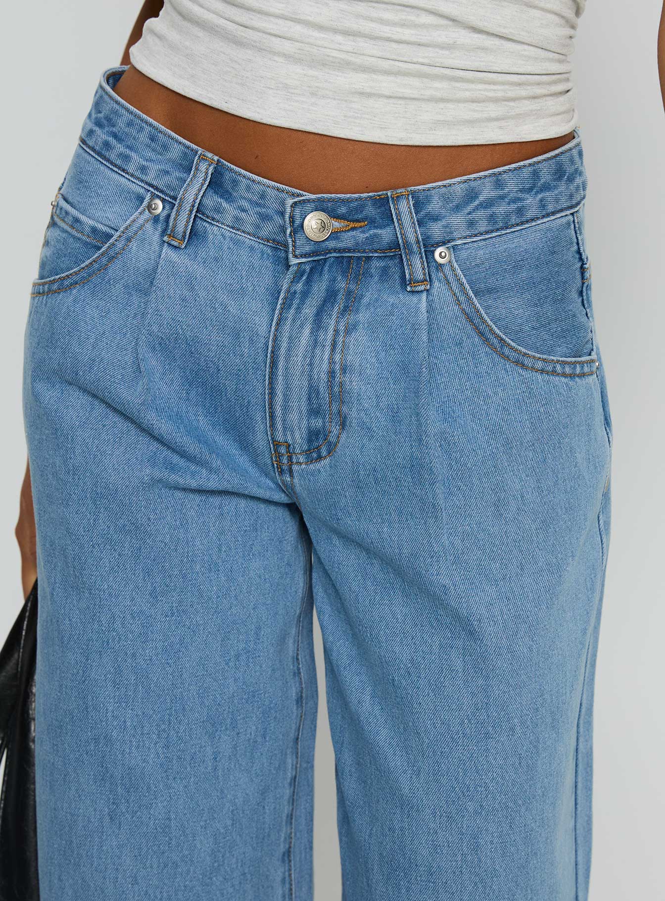 side view of model wearing Princess Polly Supercut Low Rise Baggy Pleat Jeans Light Blue Wash Low Rise Jeans 