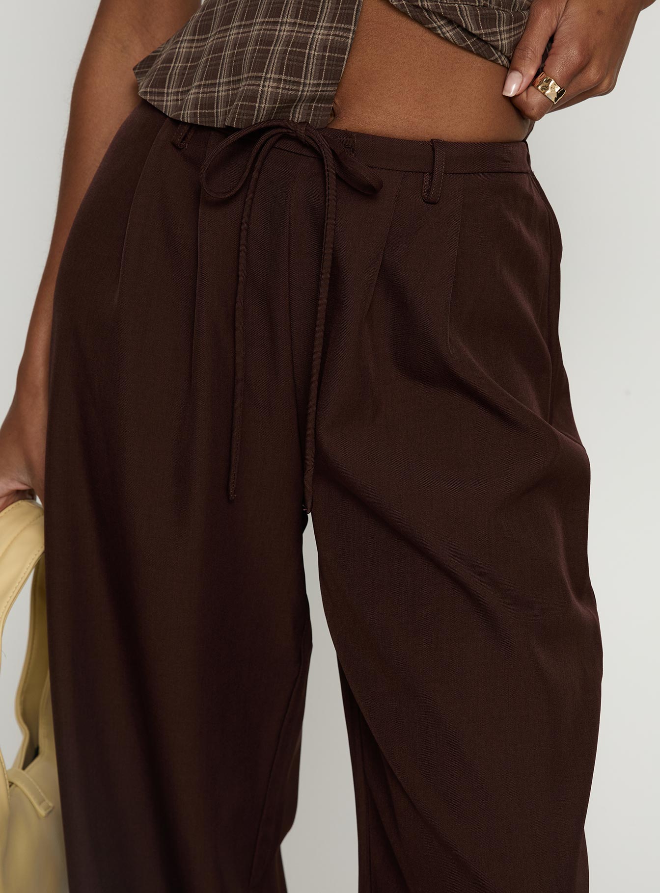 side view of model wearing Princess Polly Idolised Pleated Tie Waist Pant Chocolate Brown Mid Rise Pants 
