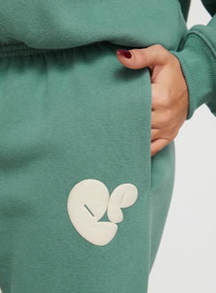 side view of model wearing Princess Polly Princess Polly Track Pants Bubble Text Sage / Eggshell Mid Rise 