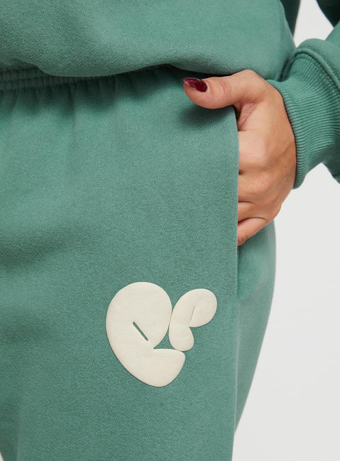 side view of model wearing Princess Polly Princess Polly Track Pants Bubble Text Sage / Eggshell Mid Rise 