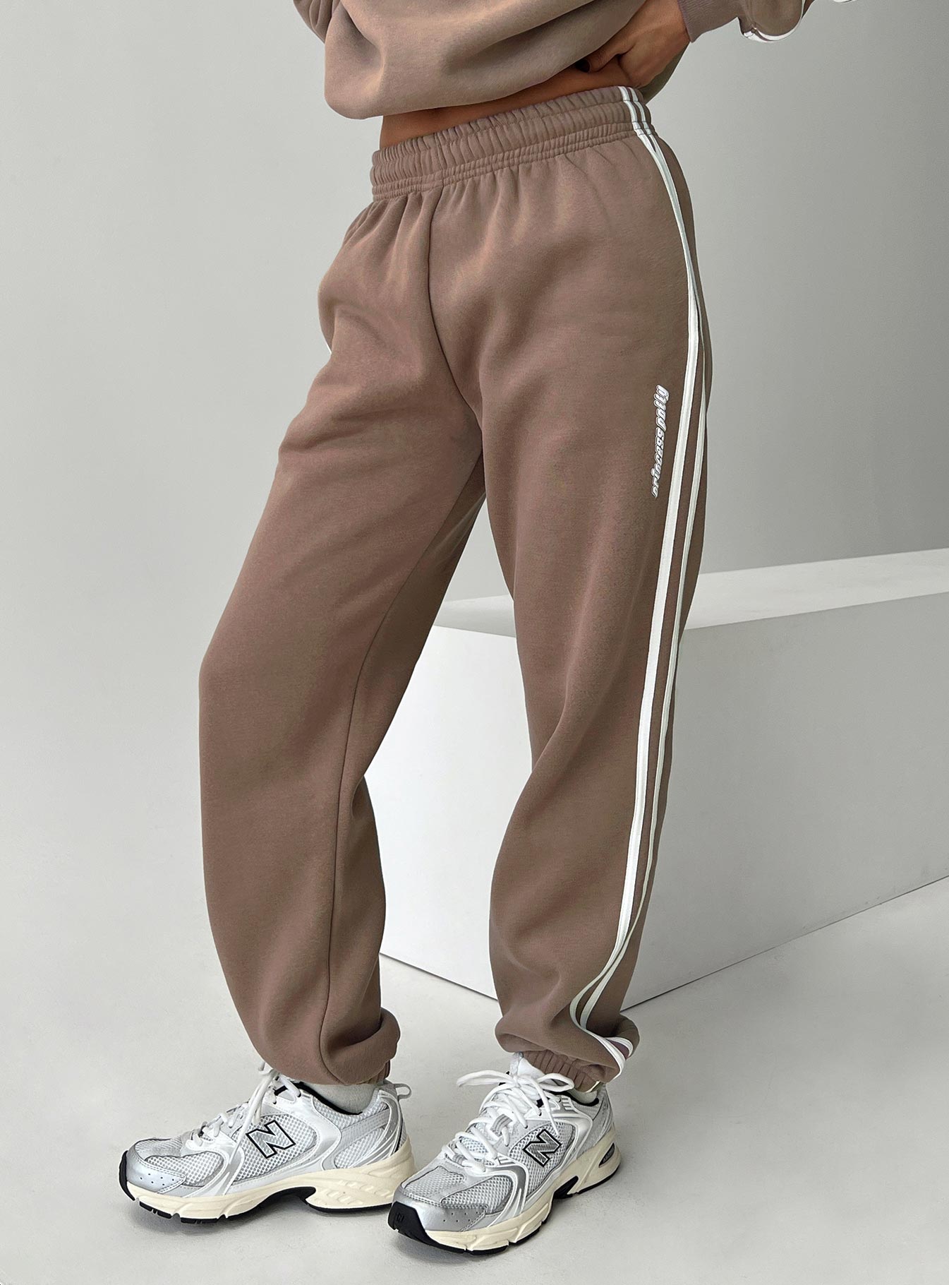 side view of model wearing Princess Polly Princess Polly Track Pants Stripe Taupe / White High Waisted Pants 