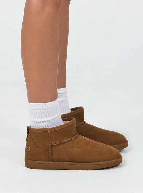 Shearling boots Princess Polly Exclusive Cropped ankle height Faux suede material Slip on style Pull tab at back Rounded toe Fluffy lining Branded patch at back