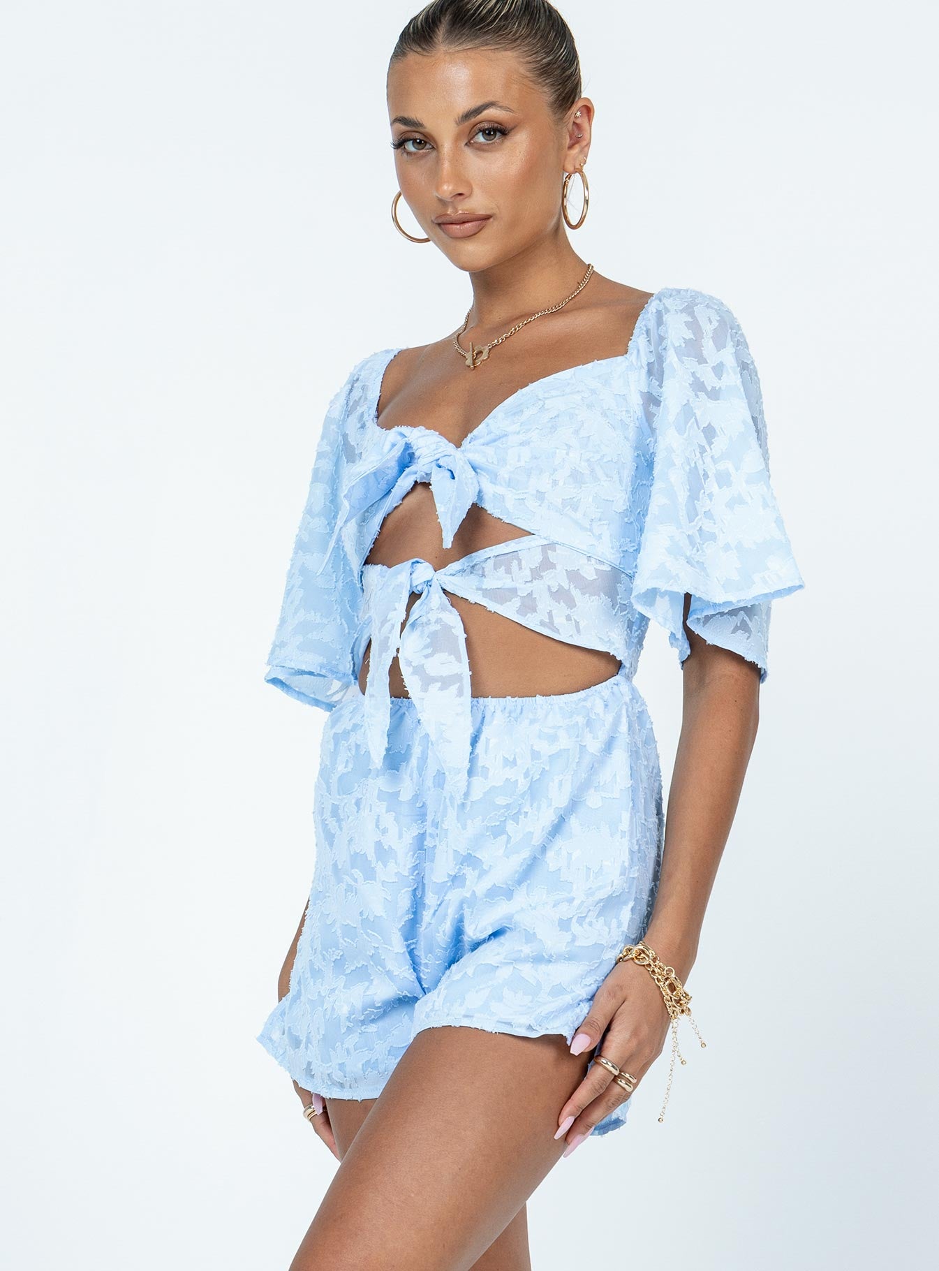 Romper Stitched floral print  Sheer material  Elasticated shoulders  Double tie front fastening  Elasticated waist  Invisible zip fastening at back 