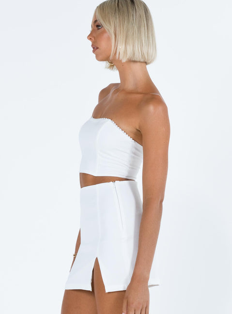 White two piece set Strapless crop top Pearl embellishments at bust Boning through bust Invisible zip fastening at back  Mini skirt Side split Invisible zip fastening at side