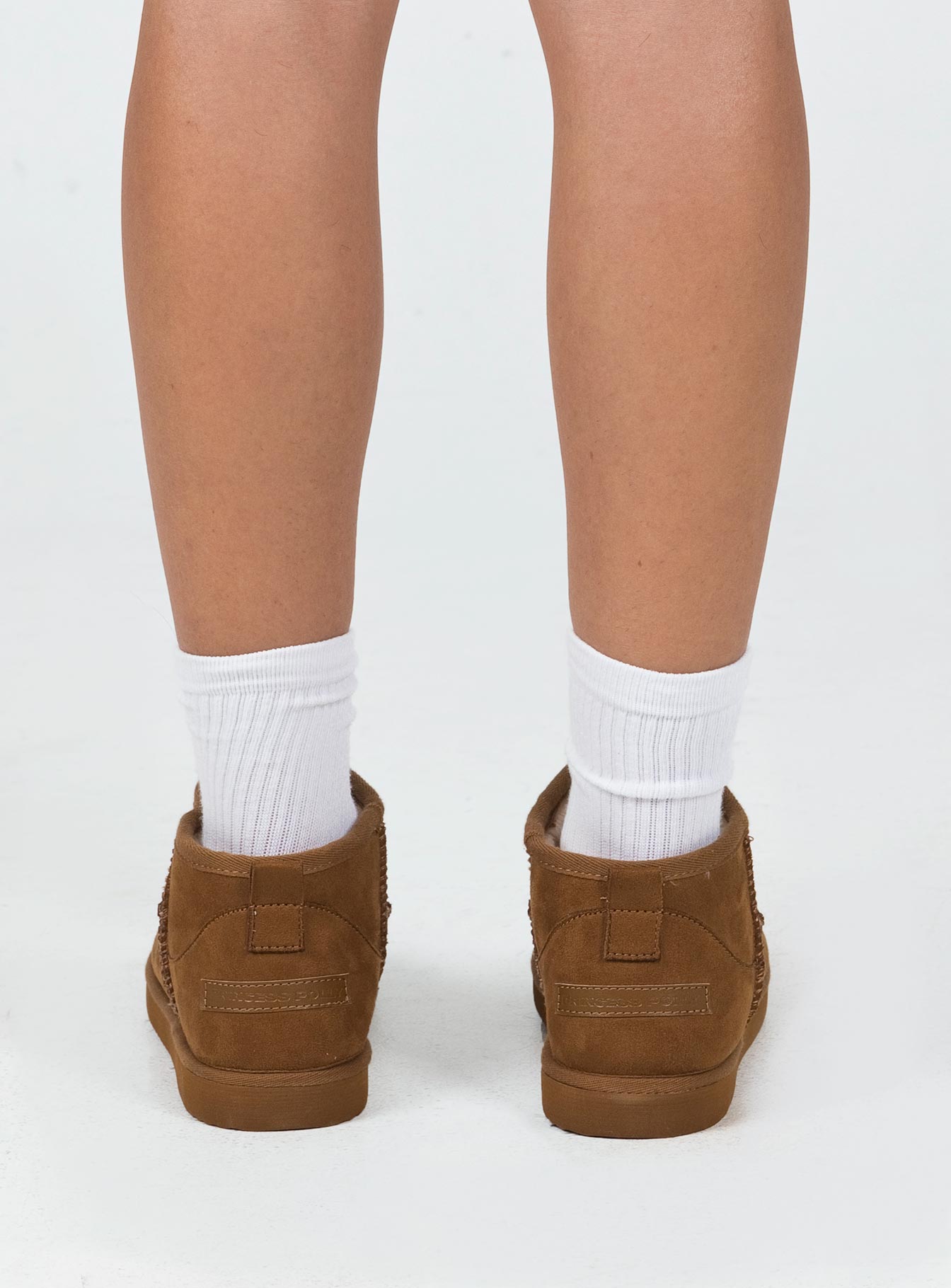 Shearling boots Princess Polly Exclusive Cropped ankle height Faux suede material Slip on style Pull tab at back Rounded toe Fluffy lining Branded patch at back