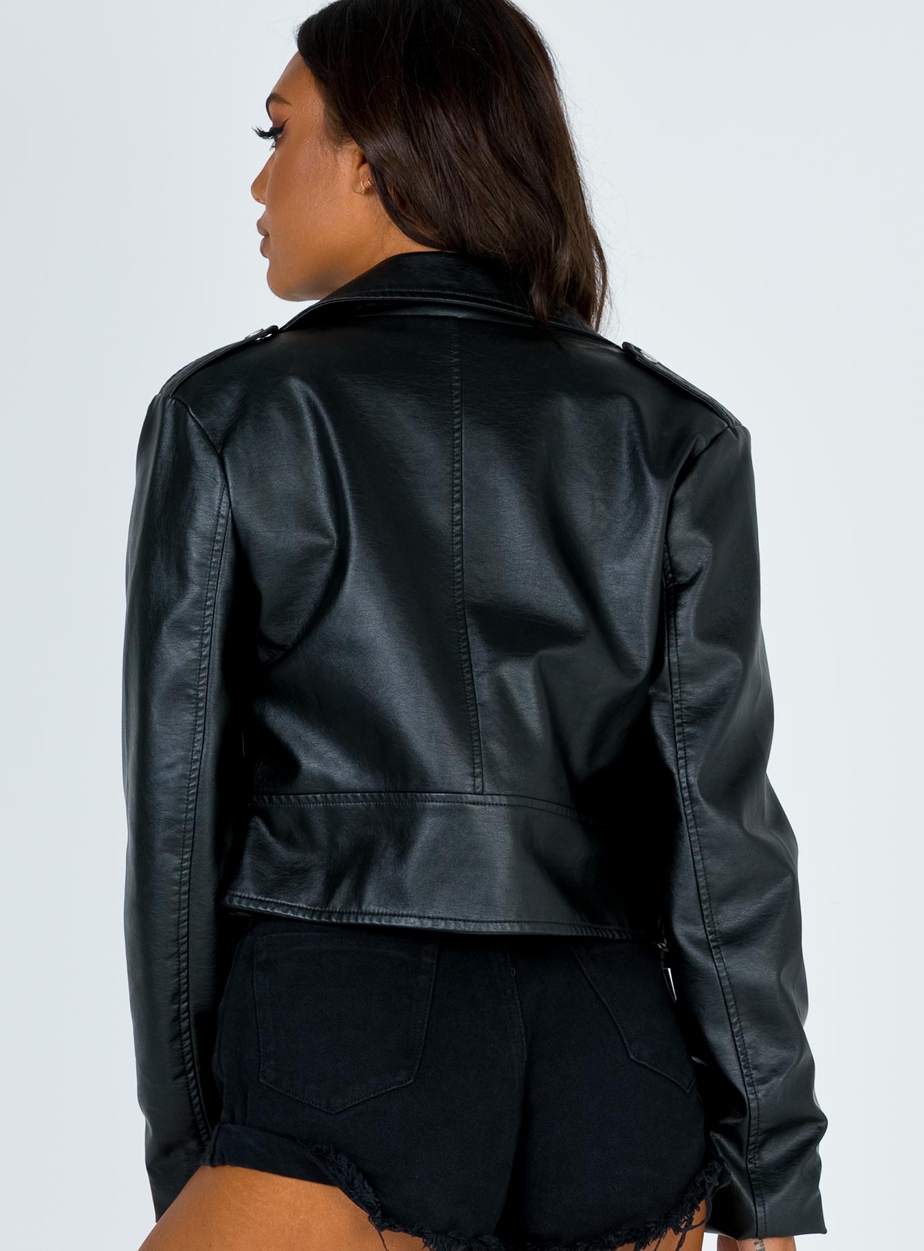 Cropped biker jacket Asymmetric zip fastening Double point collar Front zip pockets Lapels on shoulders Attached belt at waist Silver coloured hardware Vegan leather material Fully lined